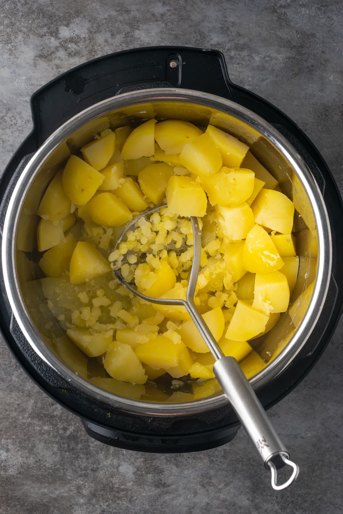 Ein Kartoffelstampfer wird verwendet, um gekochte, zerkleinerte Kartoffeln im Instant Pot zu zerdrücken.