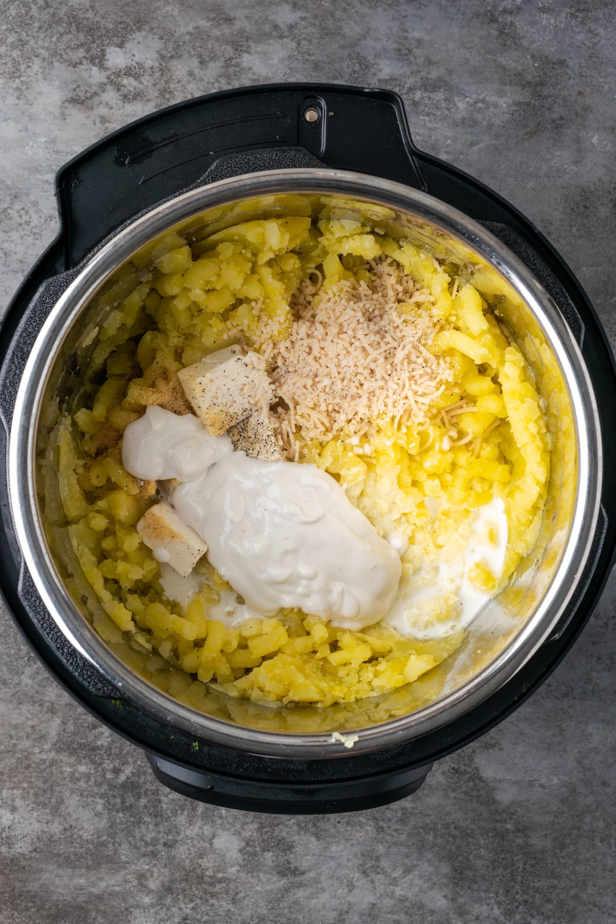 Gewürze, saure Sahne und Butter werden im Instant Pot zu Kartoffelpüree verarbeitet.