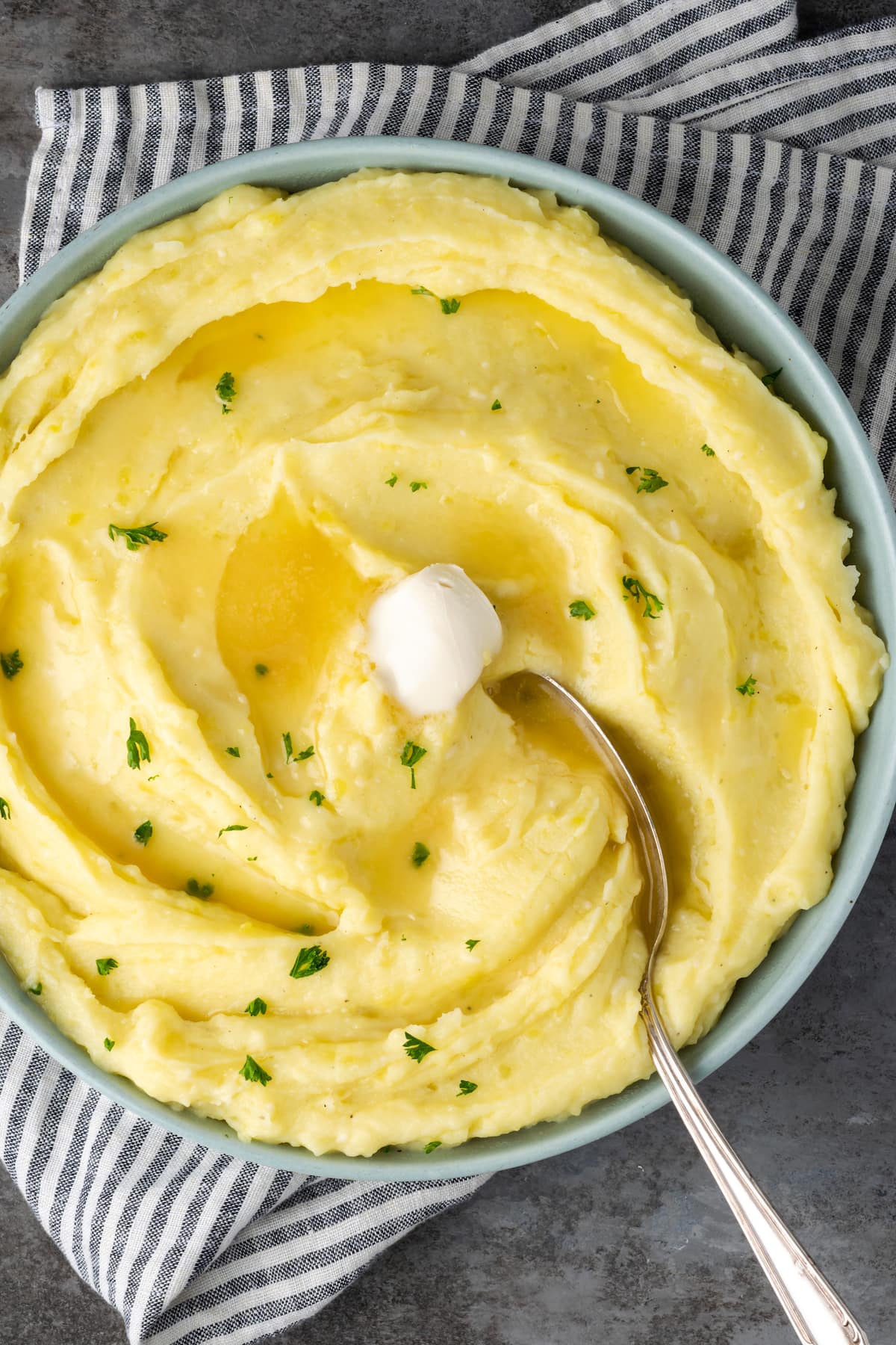 Ein Löffel in einer Schüssel mit cremigem Instant Pot-Kartoffelpüree, übergossen mit Butter.