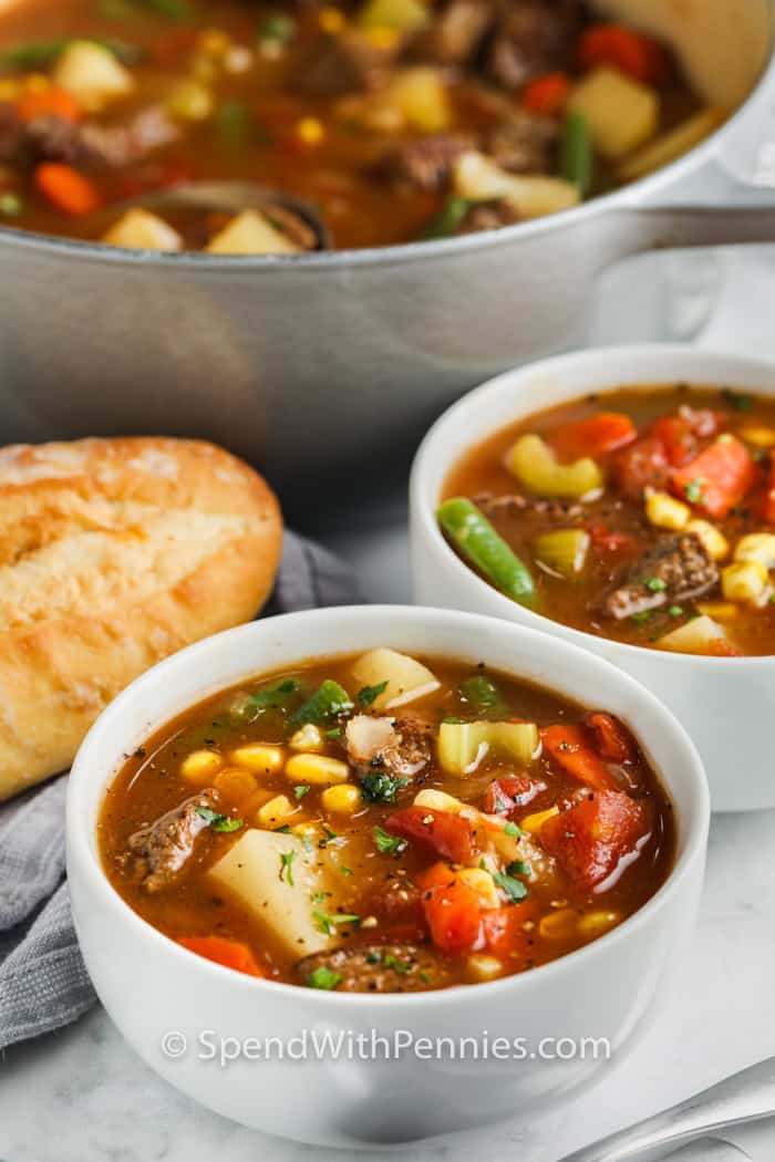 Schalen mit Gemüse-Rindfleisch-Suppe mit einem vollen Topf im Hintergrund