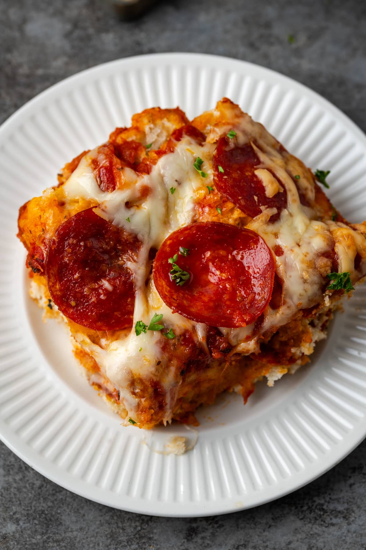Draufsicht auf eine Portion Pizzaauflauf auf einem weißen Teller.