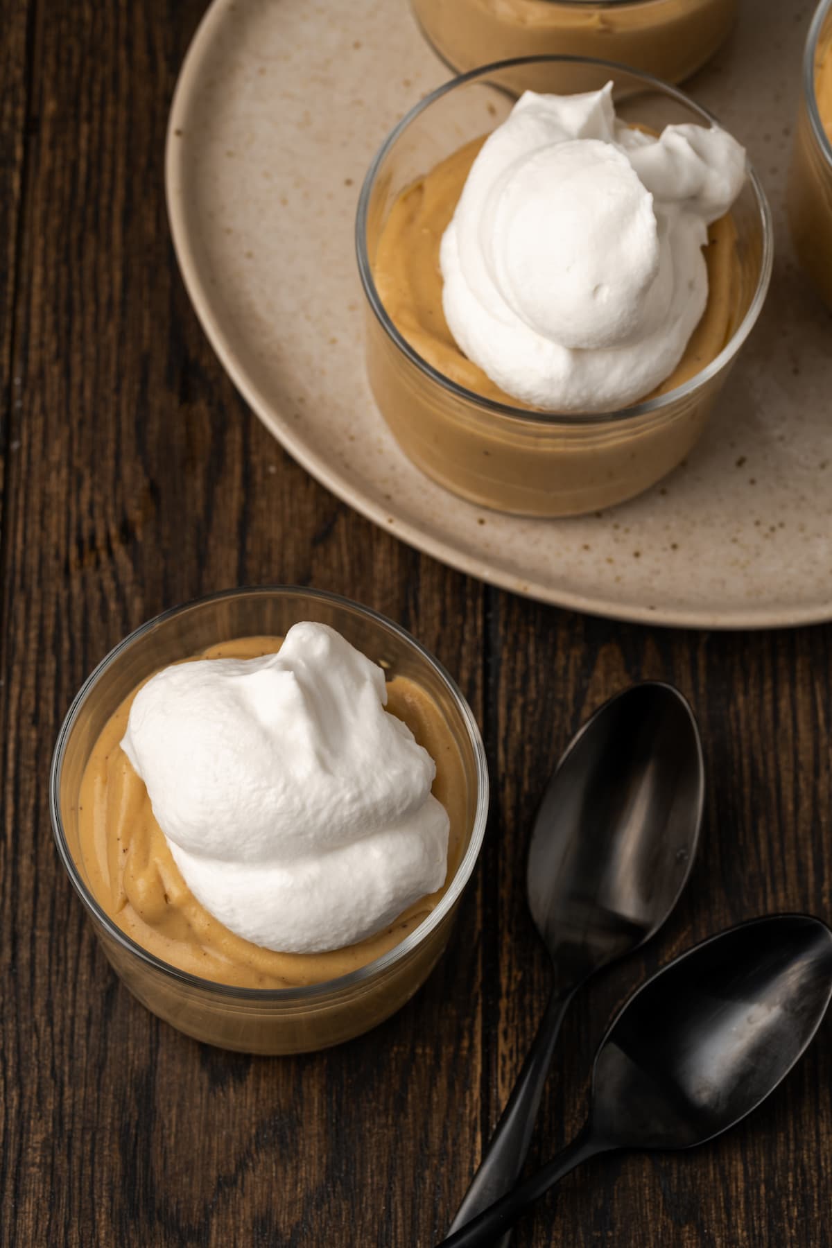 Draufsicht auf den Bourbon-Butterscotch-Pudding, der in Gläsern mit Schlagsahne serviert wird.
