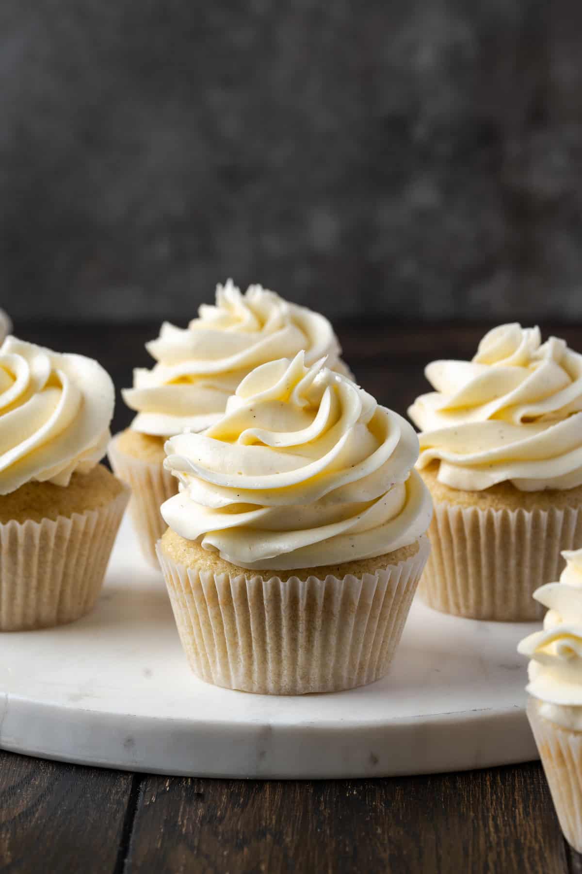 Cupcakes mit Wirbeln aus Schweizer Baiser-Buttercreme auf einem Marmorkuchenständer.