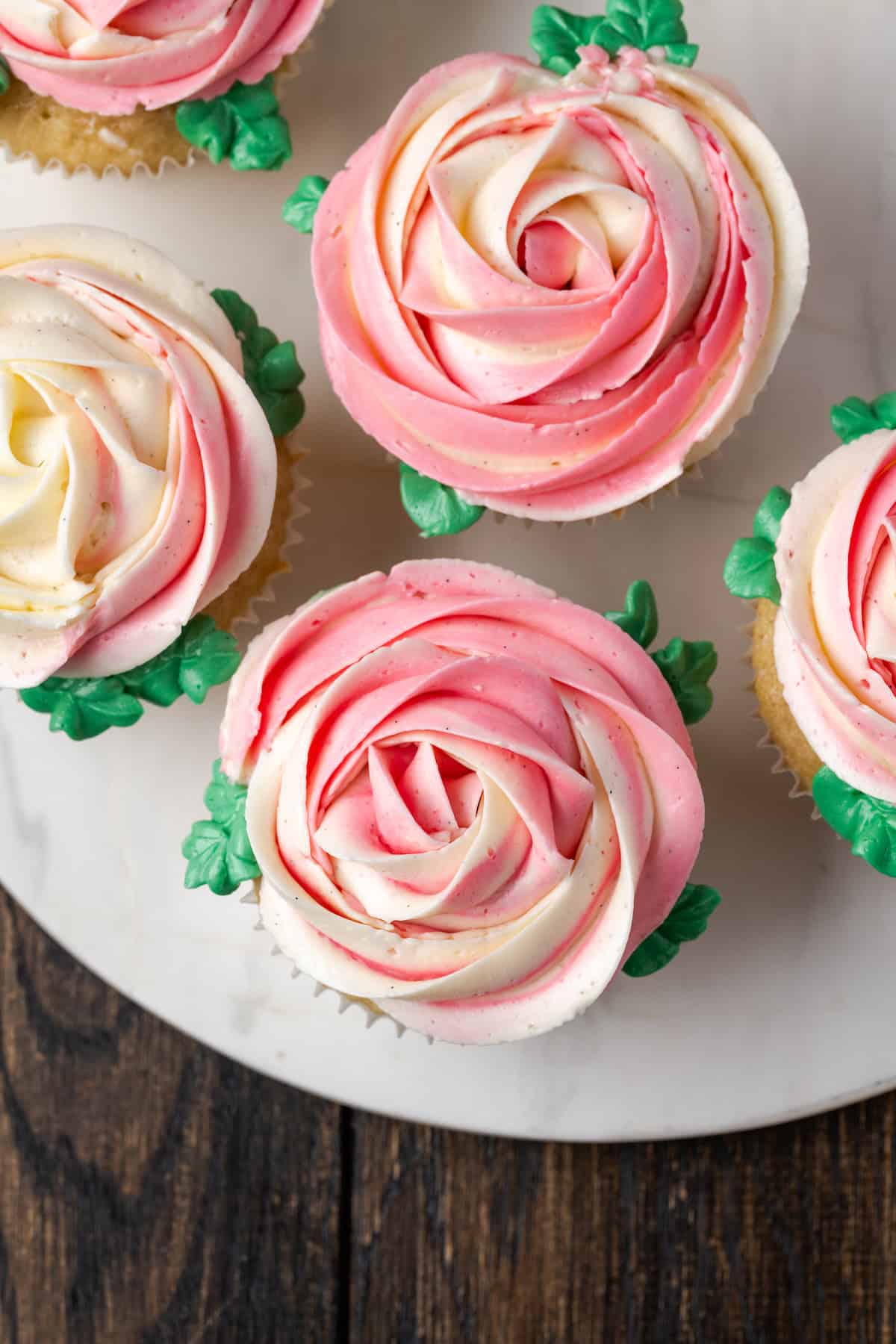 Draufsicht auf Cupcakes, die mit rosa und weißen Ombre-Rosen aus Schweizer Meringue-Buttercreme verziert sind.