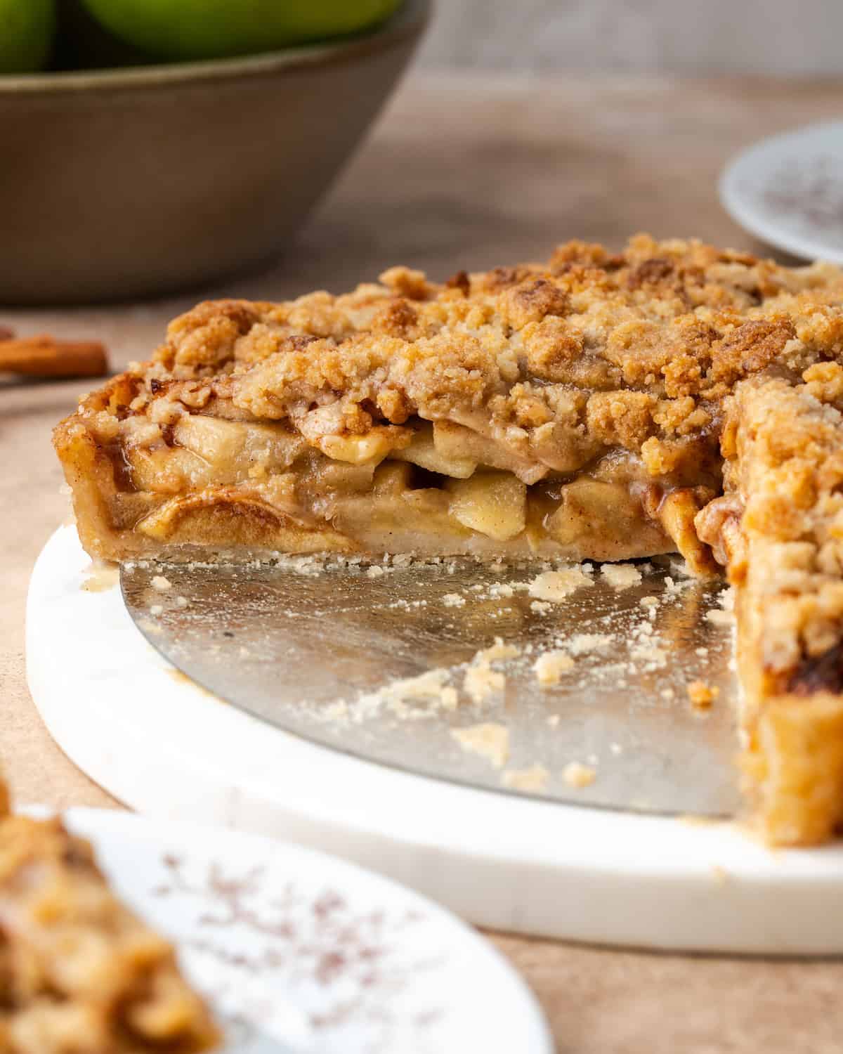 Seitenansicht einer Apfelstreusel-Torte, bei der eine große Scheibe fehlt.