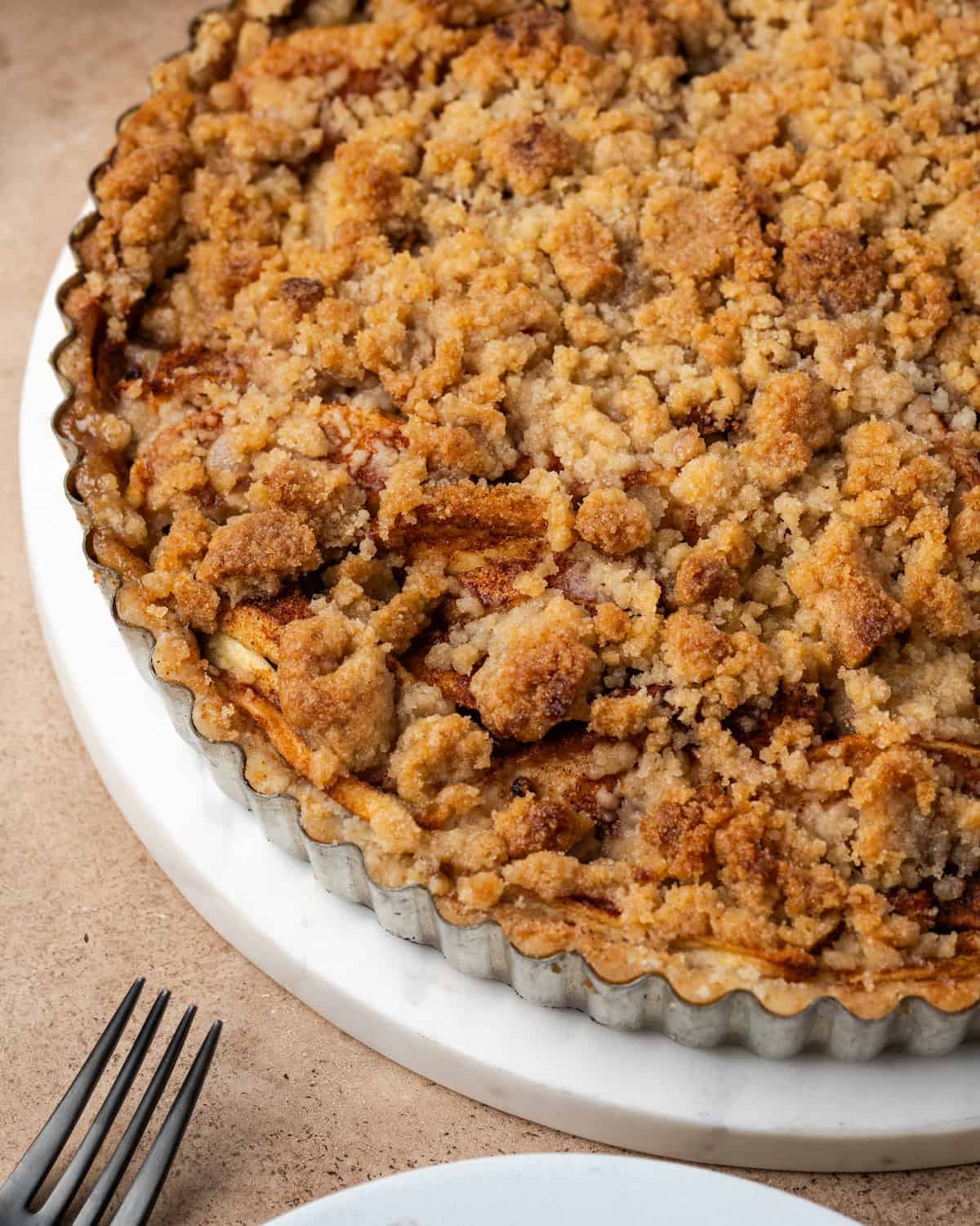 Nahaufnahme einer gebackenen Apfelstreusel-Torte in einer Tarteform.