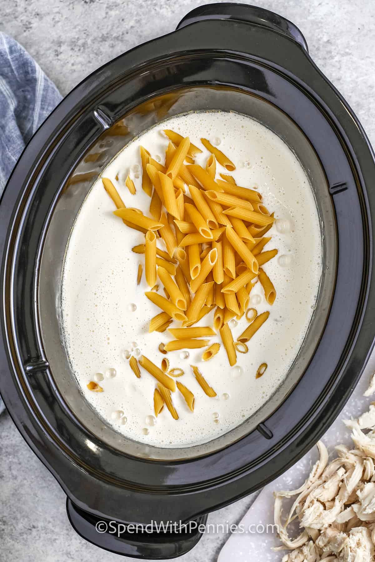 Nudeln in den Topf geben, um Crock Pot Chicken Alfredo zu kochen