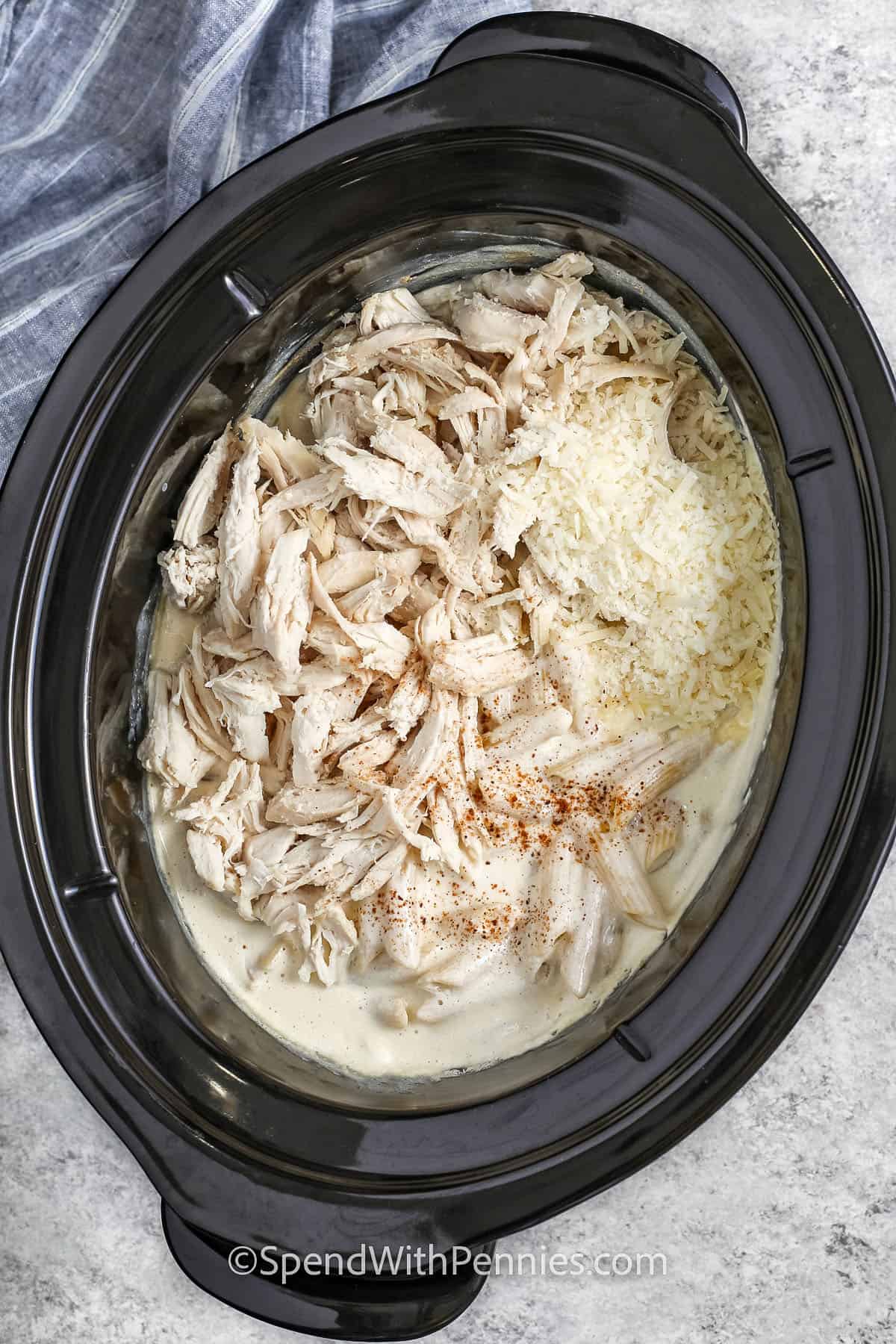 Gekochtes Hähnchen und Käse in den Topf geben, um Crock Pot Chicken Alfredo zu machen